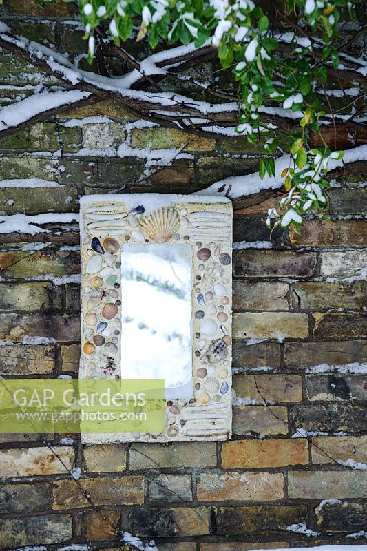 Wall plaque with mirror and sea shells reflecting snowy garden - Rhadegund House, New Square, Cambridge