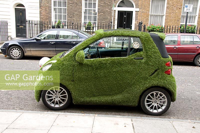 Car covered in artificial grass advertising the company supplying the product seen from side, street in Marylebone, London