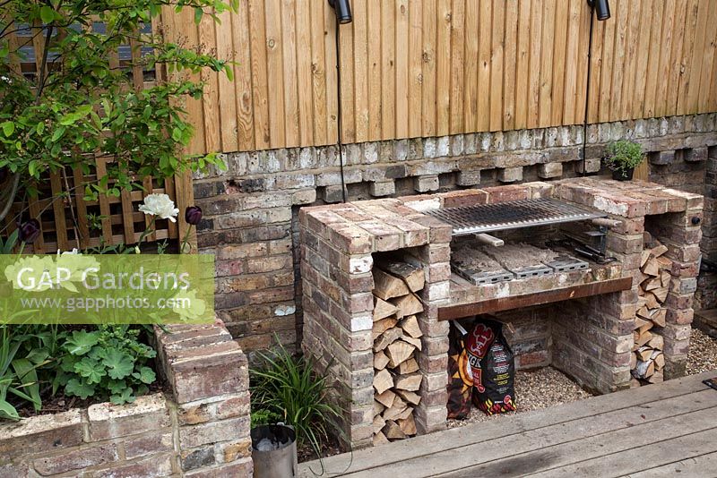 Barbecue with cut logs on decked patio area