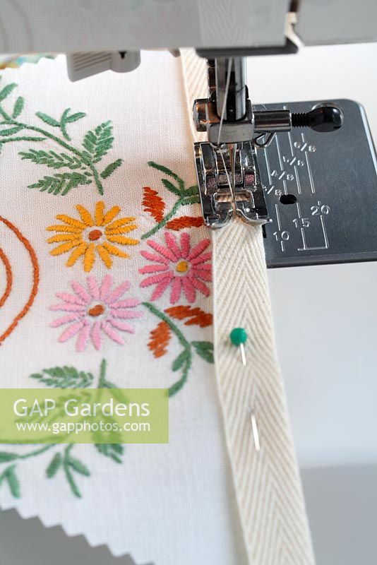 Step by step of making garden bunting with vintage linens and buttons - Using a sewing machine, sew using a straight stitch along the webbing, removing pins as you go, until all your traingles are sewn in place