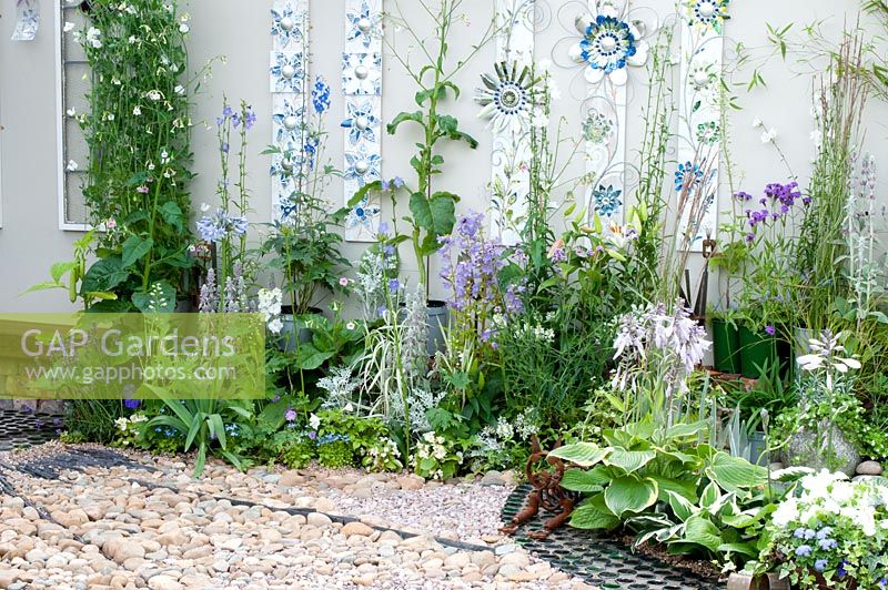 Discarded and recycled materials used to create contemporary garden with sculpture and planting in shades of green, blue and white in the 'Garden Gallery' garden. RHS Tatton Flower Show 2013