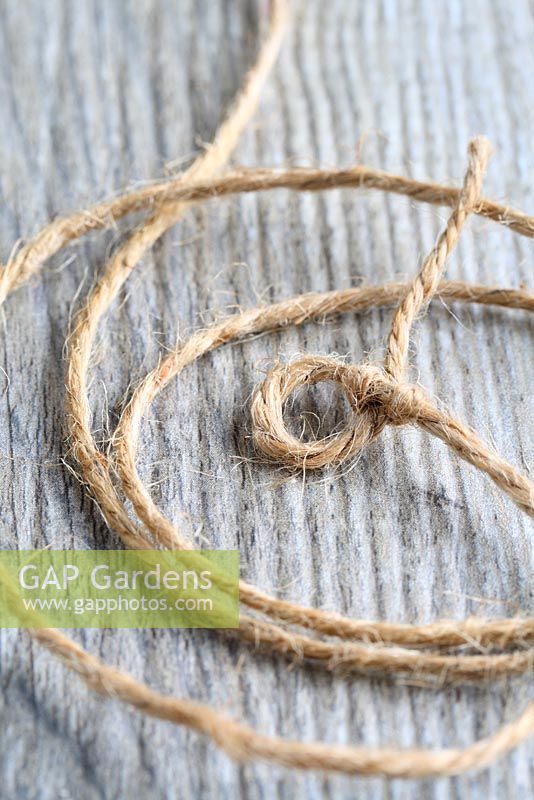 Step by step of making a simple, rustic Christmas garland with fir cones and pine needles - Tie a simple knot in one end of the twine, leaving a small loop for a drawing pin or nail to go through.