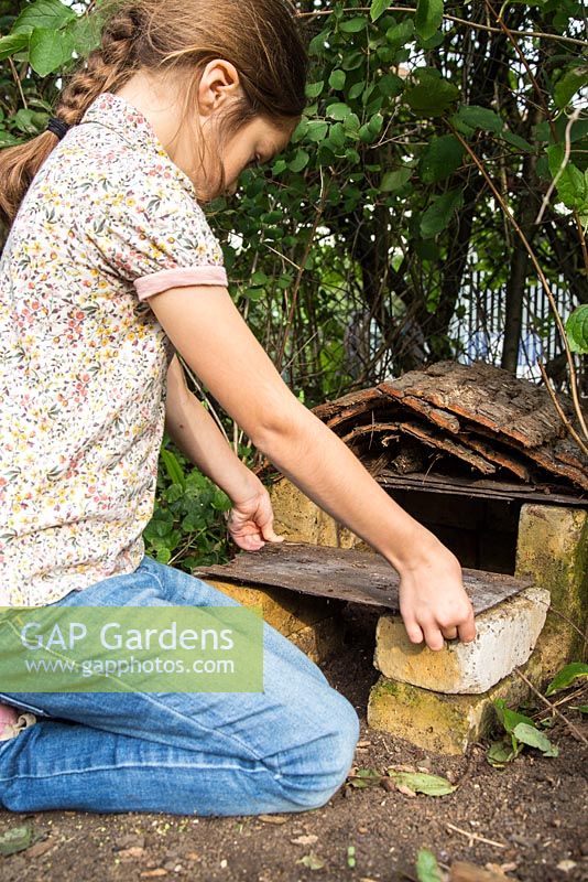 Young girl adding a piece of slate for the roof