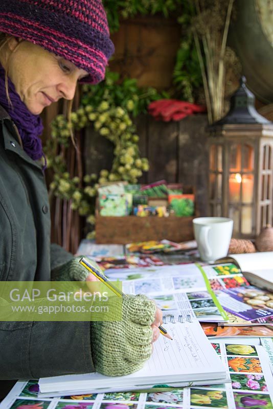 Woman sat in shed garden planning during Winter, for the following year to come.