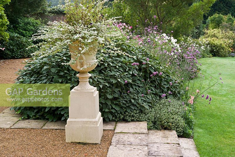 The Terrace Garden with a striking urn of Helichrysum 'Silver Mist' and Verbena bonariensis mixed with Cosmos 'Sensation Mix'  in the border