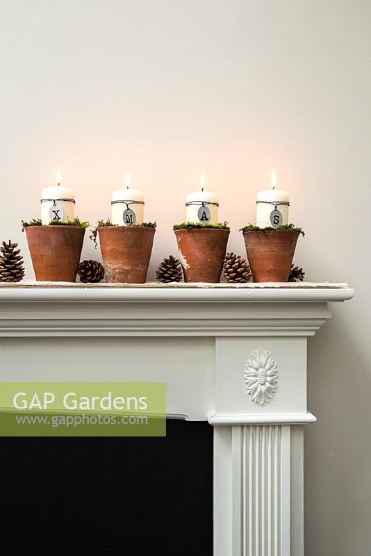 Christmas candle decorations spelling XMAS, made using terracotta pots and moss