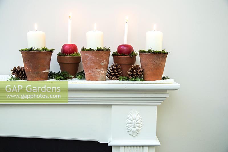 Christmas candle decorations made using terracotta pots, apples and moss