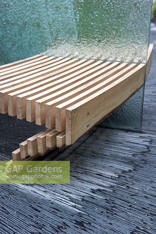 The SeeAbility Garden.  Detail of wooden seating with sheets of glass and slate flooring. 
