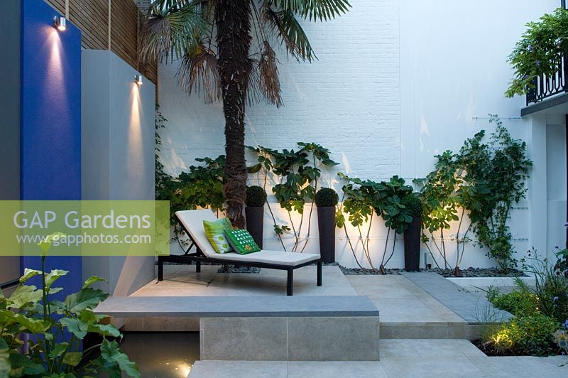 Wall panels with downlights in small urban garden. 