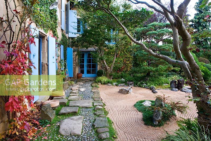 Japanese style garden - view to the east side of the house with blue shutters, path with pebbles and rocks, gravel garden and clipped scots pine