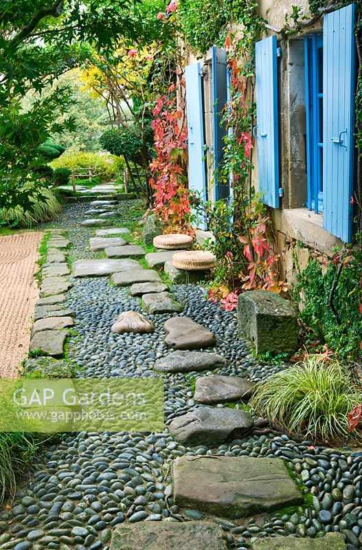 Japanese style garden - view to the east side of the house with blue shutters, path with pebbles and rocks and gravel garden