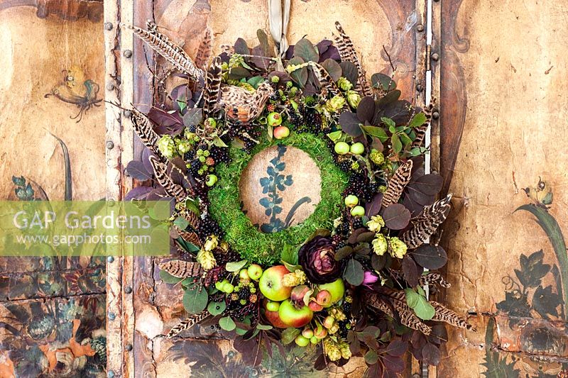 Decorative autumn wreath with feathers hanging on old distressed screen
