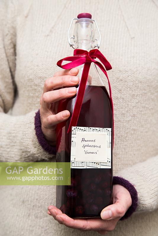Woman holding bottle of sloe gin to give as a gift