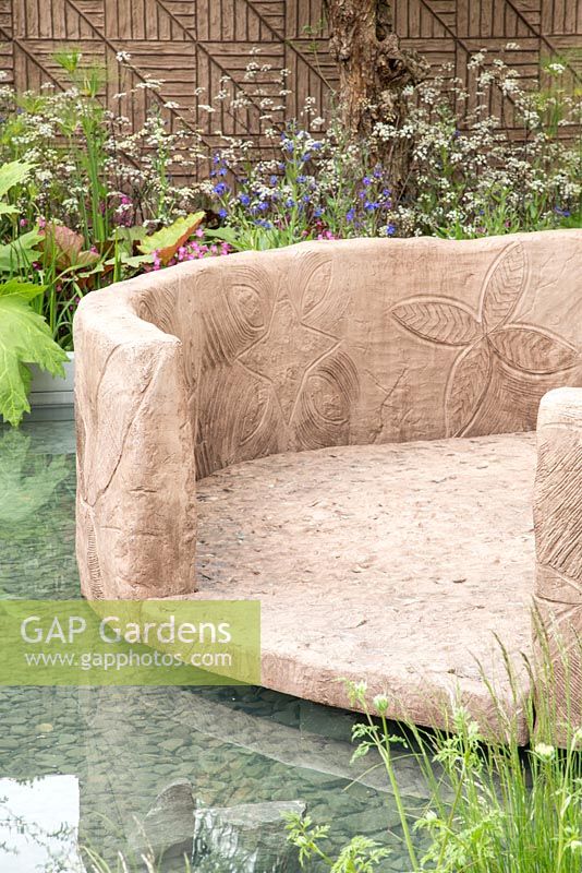 Sunken seating area surrounded by Rheum palmatum, Anthriscus sylvestris 'Ravenswing' and Myosotis sylvatica 'Bluesylva'. Show Garden: B and Q Sentebale Forget-Me-Not Garden.