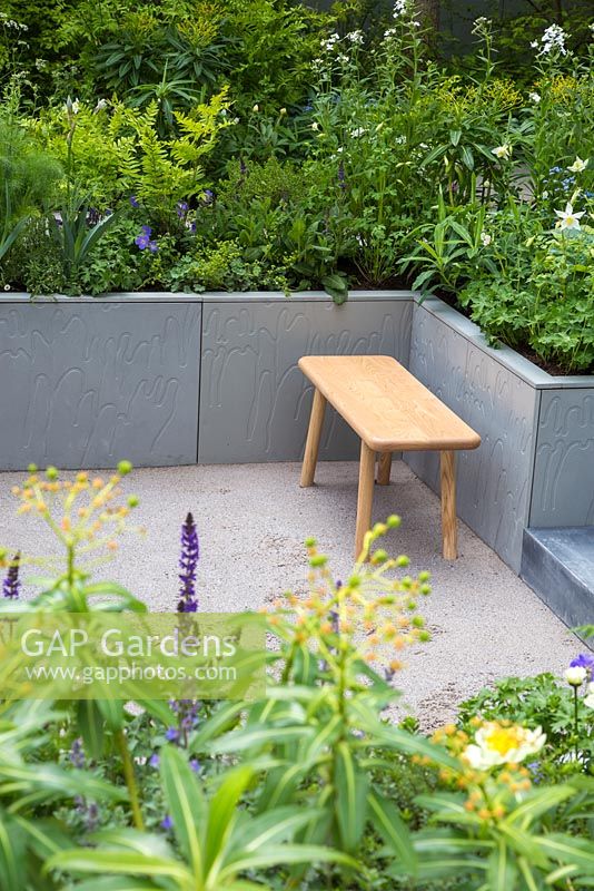 Sunken garden with seating area. Aquilegia 'White Star', Brunnera macrophylla 'Jack Frost', Euphorbia x pasteurii, Hesperis matronalis albiflora, Paeonia 'Claire de Lune' and Salvia x sylvestris 'Mainacht'. Show Garden: Stop the Spread. 
