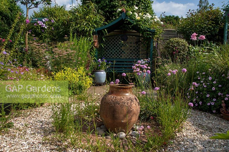 Arbour seat and garden urn in the gravel garden, Bens acre, West Sussex, owned and designed by Pauline Clarke