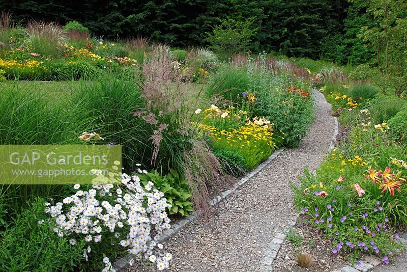 Path running through borders of Coreopsis 'Zagreb', Erigeron 'Sommerneuschnee' and Calamagrostis
