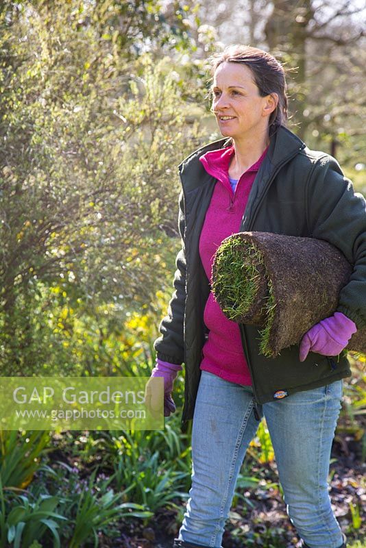 Woman carrying turf roll for resurfacing lawn