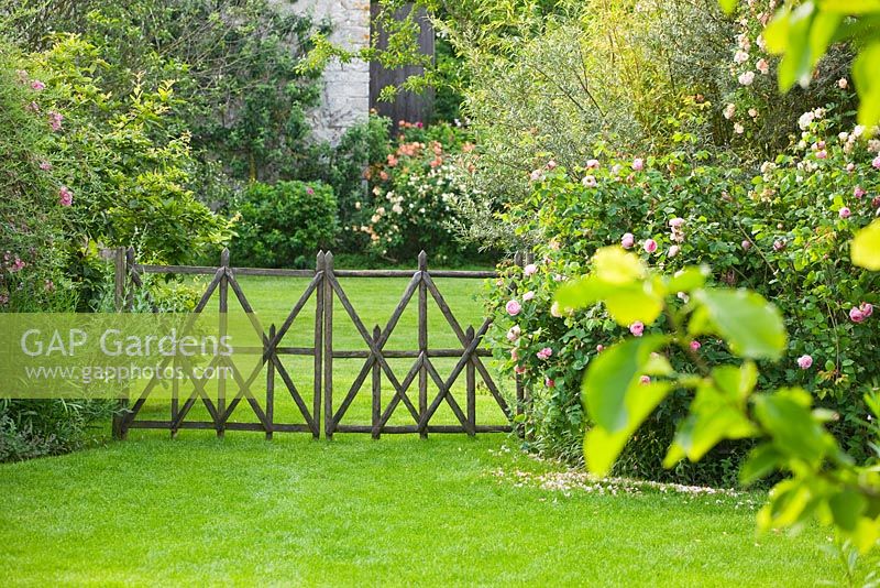 Lawn and a decorative wooden fence by Stephane Cassine. Les Jardins de Roquelin, Loire Valley, France