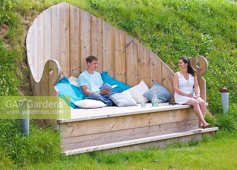 The throne - people relaxing on deck seat that is set into the hillside with blue and white cushions 