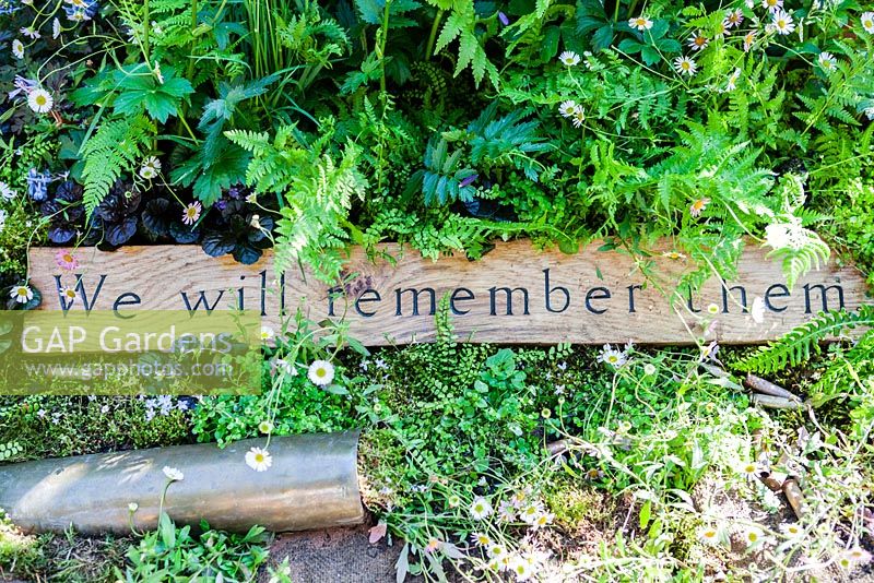 Detail of wooden sign 'We will remember them' with shell casings. The DialAFlight Potter's Garden. RHS Chelsea Flower Show 2014. 
 