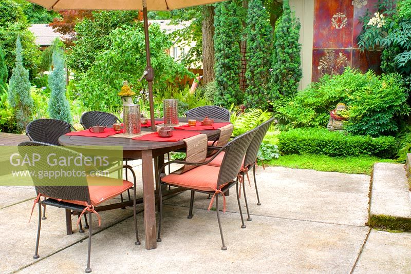 Summer outdoor dining area and patio surrounded by lush gardens. Nandina domestica -Heavenly Bamboo, Taxus baccata 'Fastigiata' - Irish Yew.