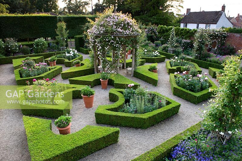 Aerial view of parterre garden with romantic English traditional style with layout of box hedging infilled with peonies and a central arbour covered with climbing rose - Seend, Wiltshire