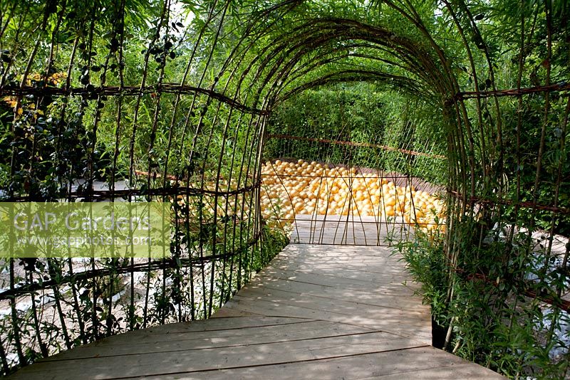 Title: Ma Cassette. Corridor made of willow branches and modern sculpture with golden painted balls.