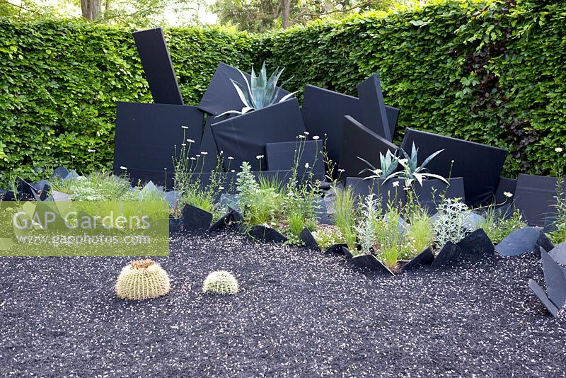 Title: Paradis inverse. Big black ornaments and black slates planted with Agave americana and black rubber on the surface.