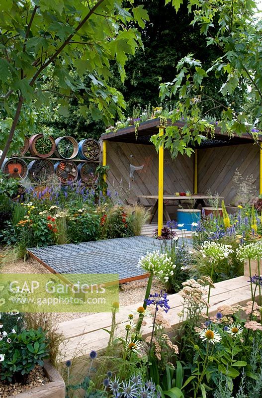 Metal A Space to Connect and Grow. View into garden with recycled mesh flooring over gravel and wooden loggia meeting space. Colourful planting with white agapanthus and echinacea. Designer: Jeni Cairns and Sophie Antonelli Sponsor: Metal Gold award best summer garden