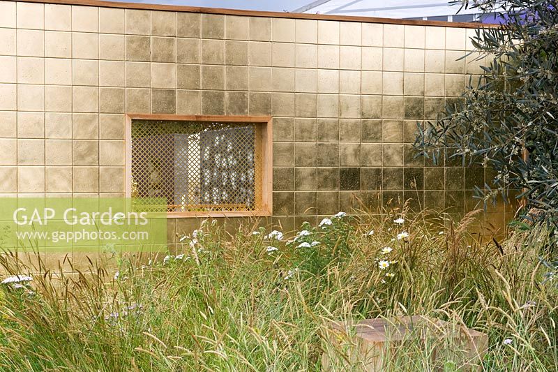 Greed Dichotomy Garden gold gilt tiled with mesh window representing confessional screen. Religious symbols. Long meadow grass.  Designer: Sara Jane Rothwell and Joanma Roig 