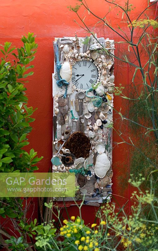 Shell clock on wall in coastal garden 