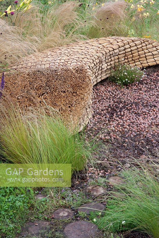 Jordans Wildlife Garden - view of garden seat bench made from straw thatch with mulch of hazelnuts 