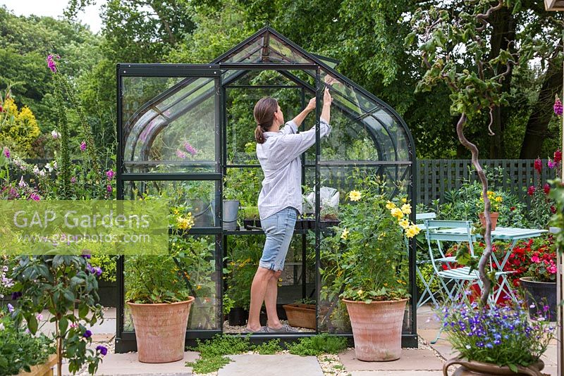 Woman opening the windows of a Greenhouse to allow air flow