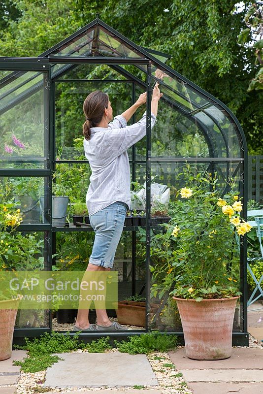 Woman opening the windows of a Greenhouse to allow air flow