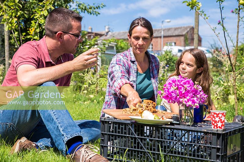 Family eating a picnic lunch at an allotment plot