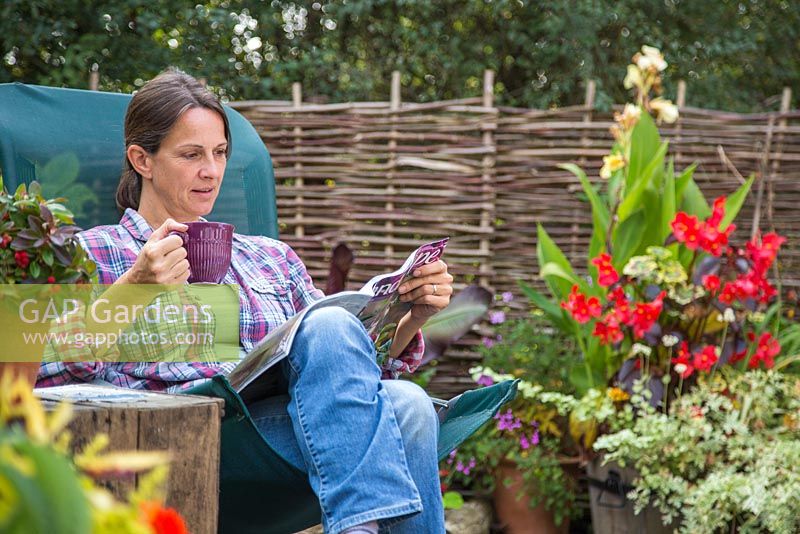 Woman reading a magazine, relaxing in her garden retreat.