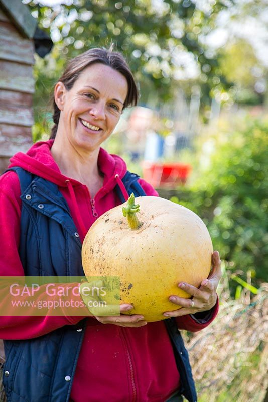 Proud woman holding harvested Pumpkin Hundred Weight. 