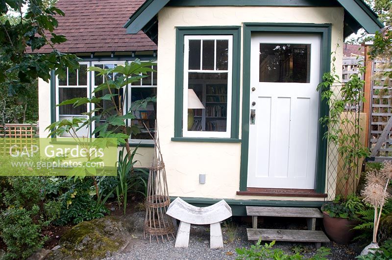 Backdoor entrance to house with Tetrapanax wooden teepee and stool. Victoria BC, Canada