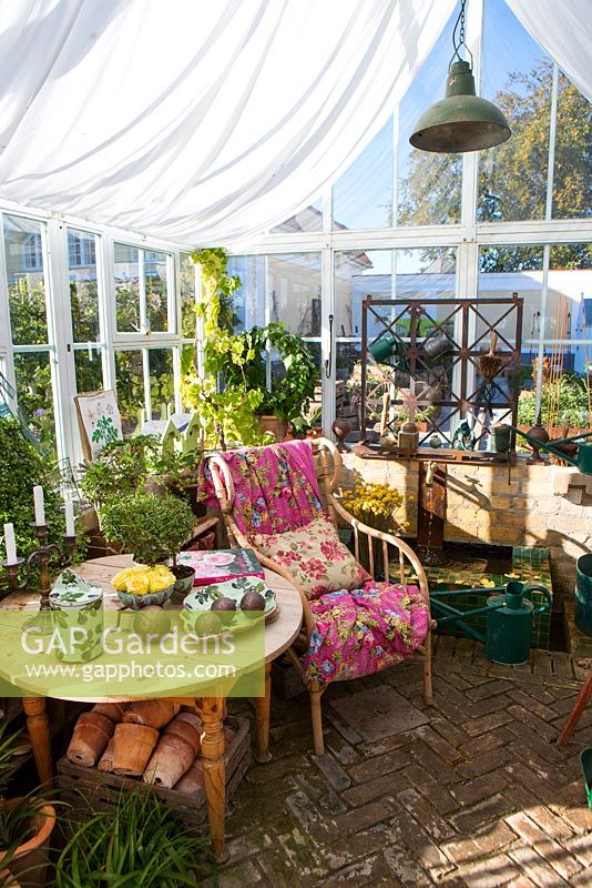Wicker chair, wooden table, seating area in greenhouse 