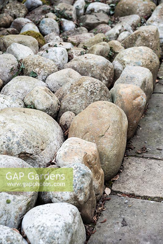Large pebbles, packed tightly together, used as a mulch in a formal garden. 