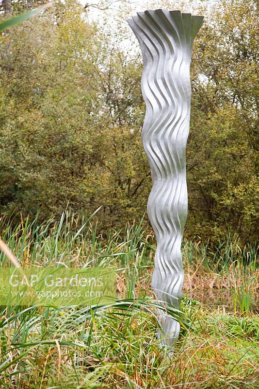 Wave by Leon Vermunt made from resin and aluminium pigment. The Hannah Peschar Sculpture Garden designed by Anthony Paul, landscape designer