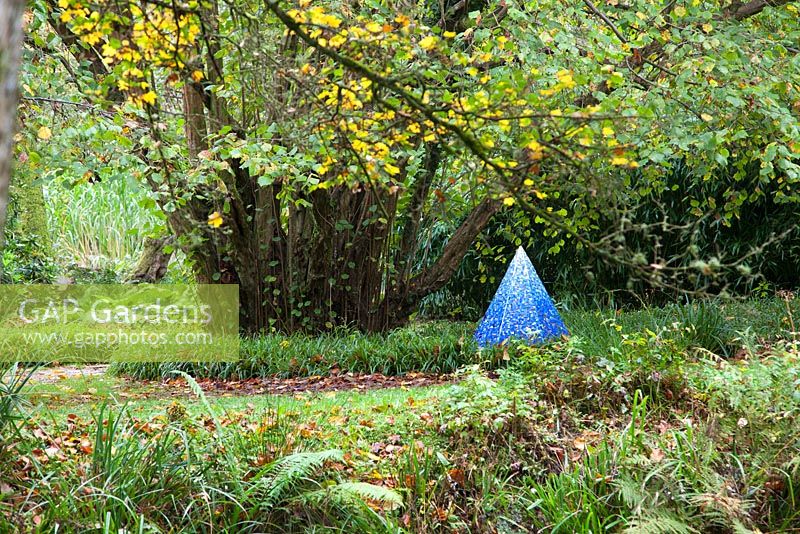 Chakra Dance by Elizabeth de Ath amongst autumn woodland gardens. The Hannah Peschar Sculpture Garden designed by Anthony Paul, landscape gardener, Surrey