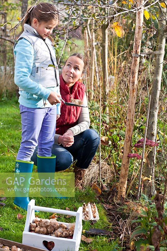 Woman and girl planting spring bulbs.