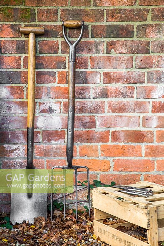 Vintage wooden fork and spade against a brick wall