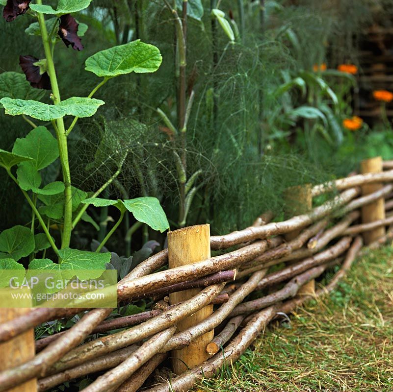 Neat edges to beds created from woven hazel on chestnut stakes.