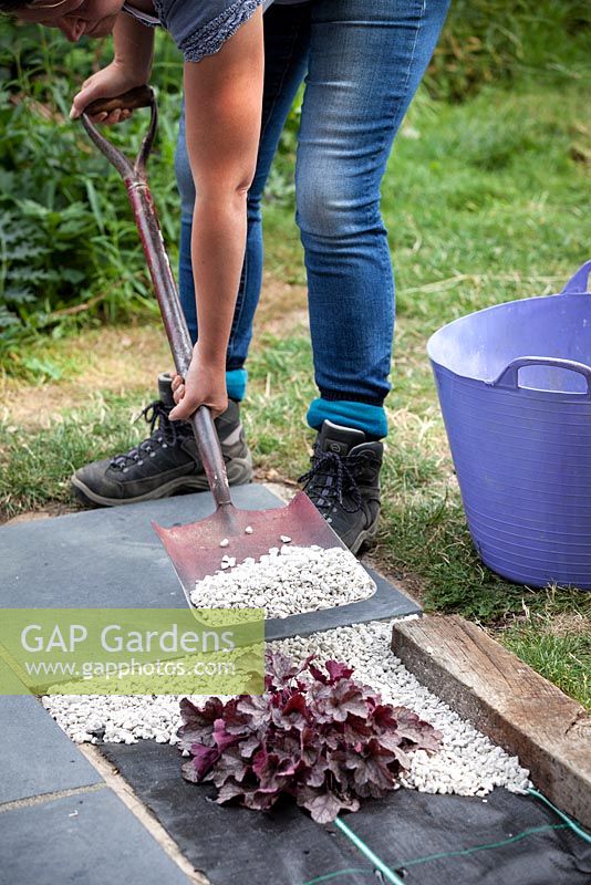 Woman placing the gravel around the plant on top of the weed suppression membrane.