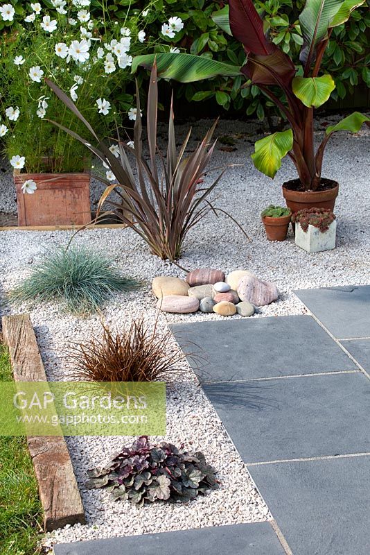 Completed gravel garden with black limestone paving and plants in Summer.