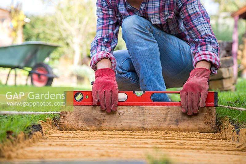 Use a spirit measure to ensure the layer of sand is flat.