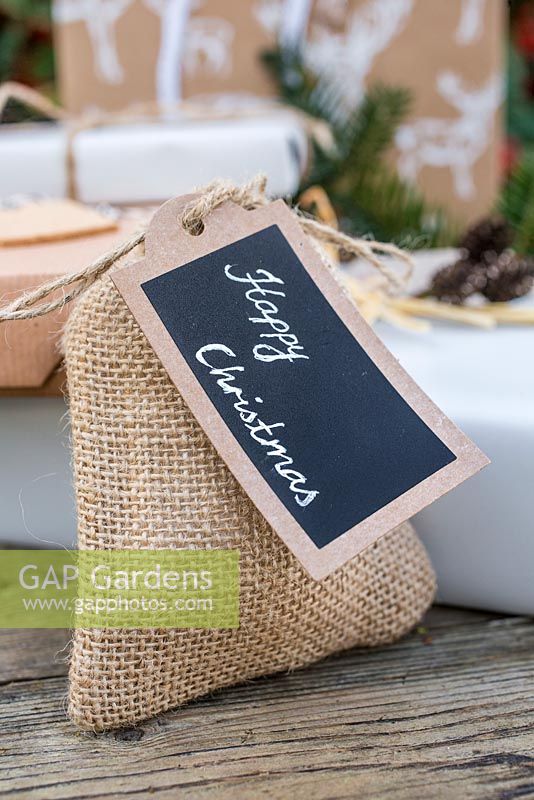 Christmas present wrapped in Hessian, accompanied with Yew foliage. Featuring cork tag and Alder decoration